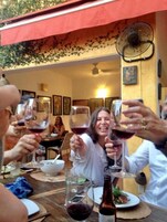 Un grupo de personas brindando con copas de vino en una mesa con un abanico y una botella de vino.