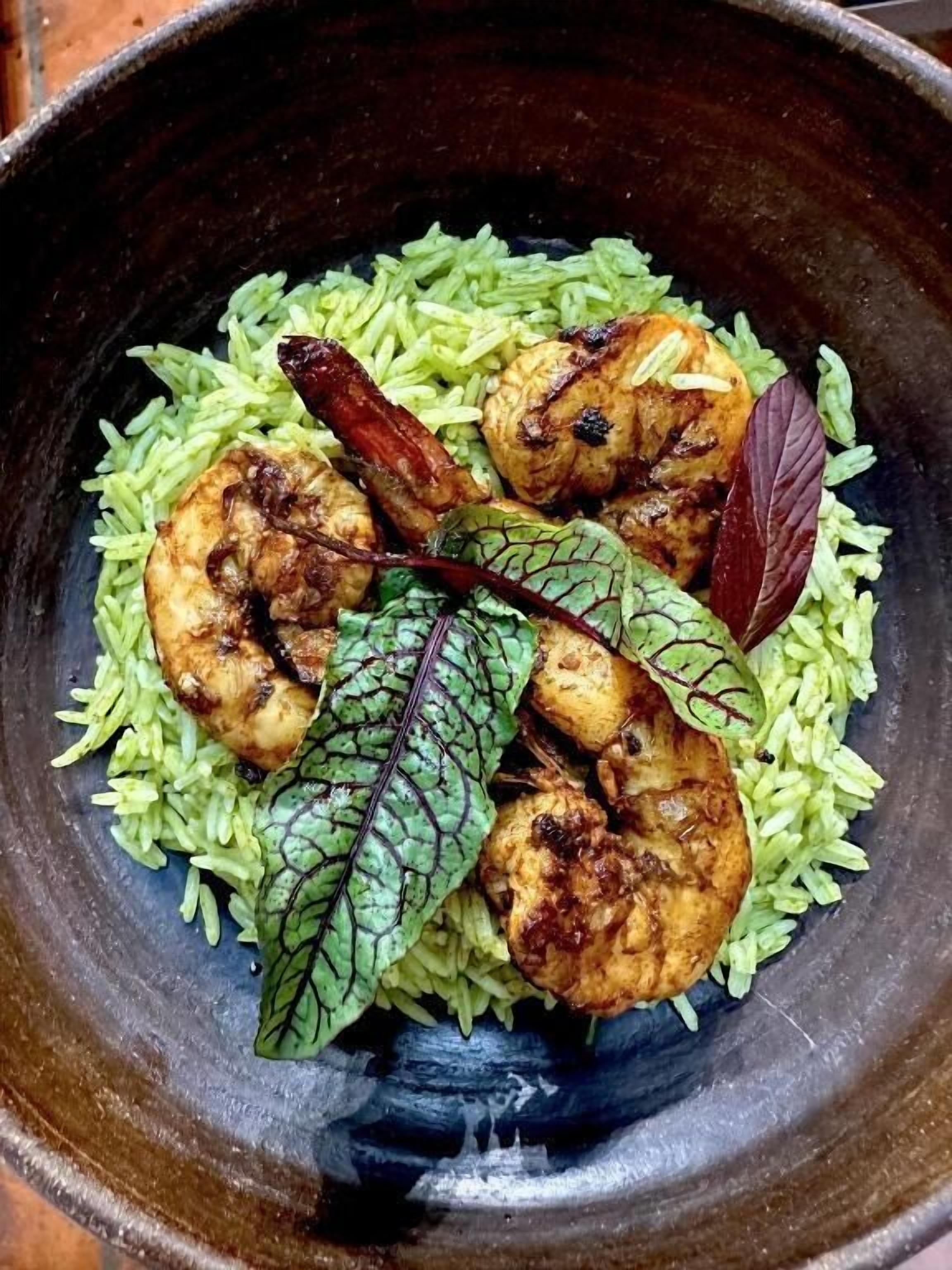Uma tigela de comida com arroz, frango e um enfeite de folha.