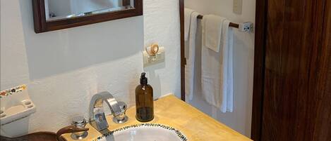 A bathroom with a beige sink, a mirror, a towel rack, and a wooden door.