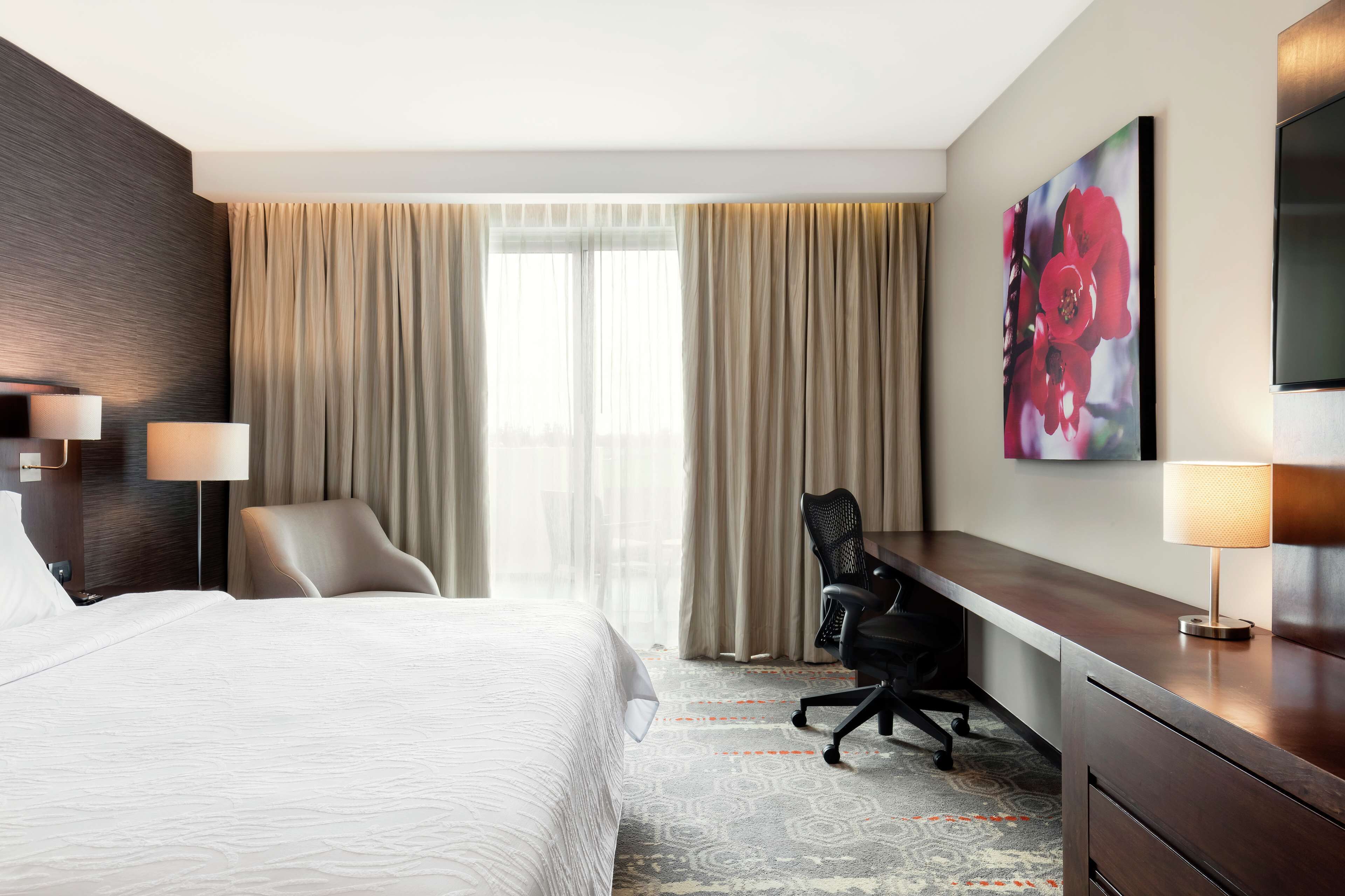 Une chambre d’hôtel avec un grand lit, un bureau, une chaise et un téléviseur.