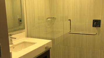 A modern bathroom with a glass shower enclosure, a vanity with a sink, and a mirror.