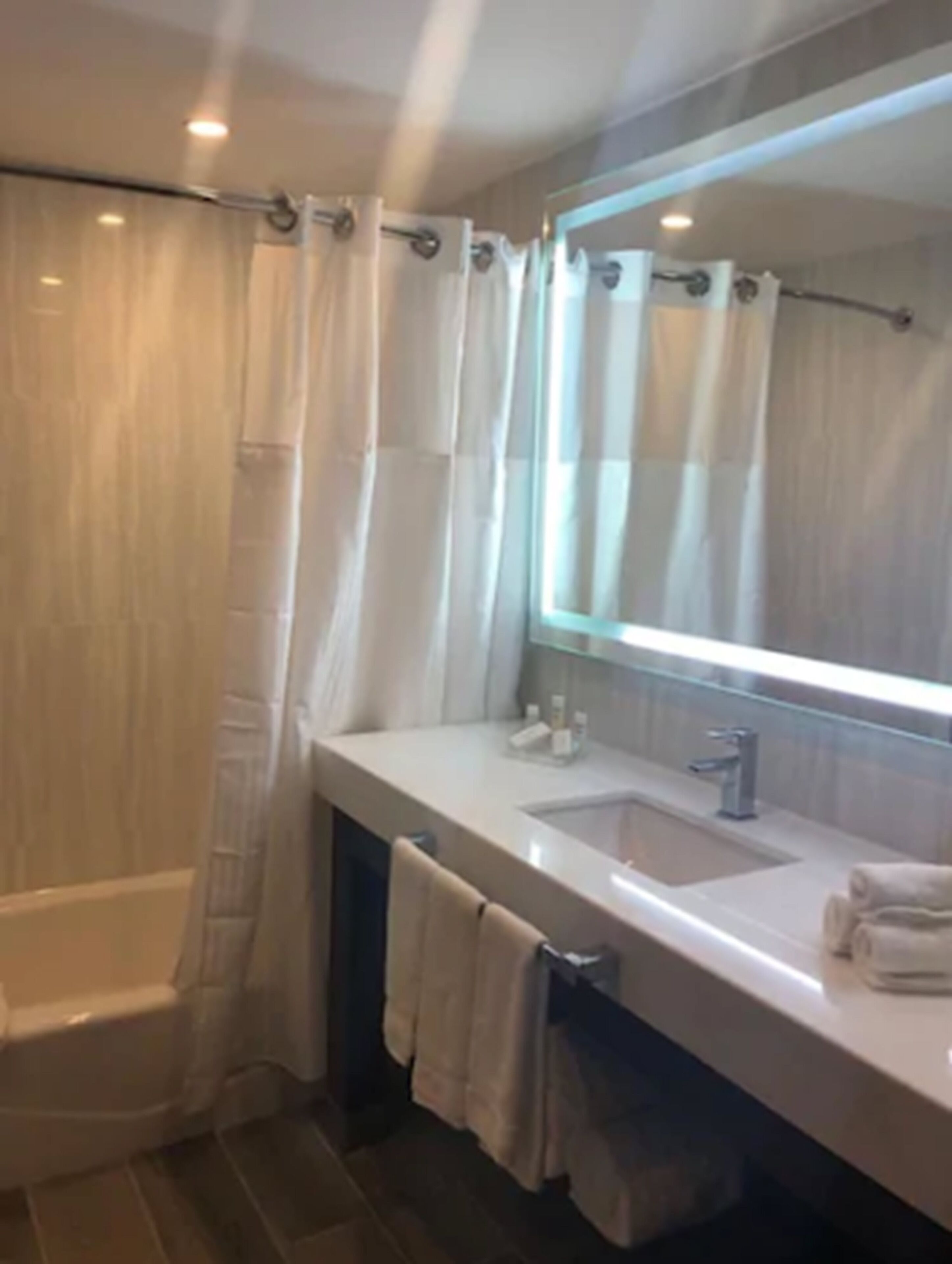 Un baño moderno con bañera, lavamanos y un espejo grande.