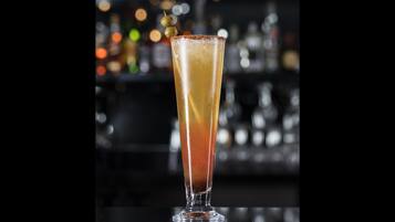 Un bicchiere alto con sfumature di colore, probabilmente contenente un cocktail, e guarnito.