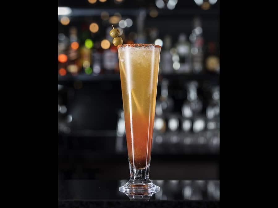Un bicchiere alto con sfumature di colore, probabilmente contenente un cocktail, e guarnito.
