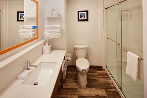 A modern bathroom with a sink, toilet, and glass shower enclosure.