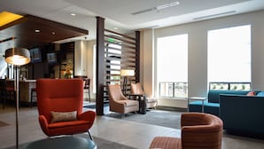 A modern lobby with a bar area, seating arrangements, and large windows providing natural light. - Hilton Garden Inn Louisville Mall of St. Matthews (Louisville)