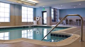 An indoor swimming pool with clear water, a lifebuoy, and a pool ladder. - Hilton Garden Inn Louisville Mall of St. Matthews (Louisville)