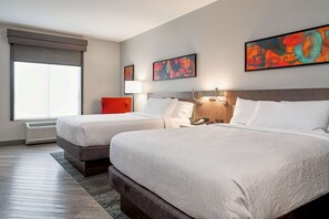 Ein Hotelzimmer mit zwei Betten, einem großen Fenster mit Blick und Bildern an den Wänden.