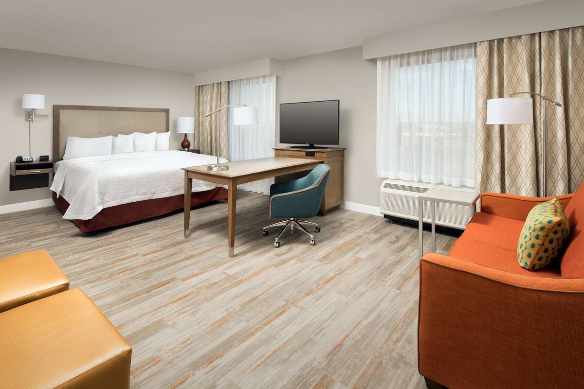 Habitación de hotel con cama, escritorio, televisión, silla y sofá.