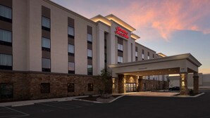 A modern hotel with a flat facade, a prominent red sign, and a covered entrance. - Hampton Inn & Suites San Antonio Lackland AFB SeaWorld (San Antonio)