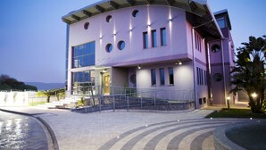 Um edifício moderno com fachada curva, várias janelas e área de entrada bem iluminada.