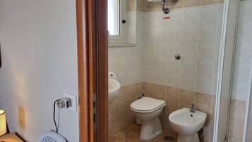 Un baño con inodoro, bidé y zona de ducha.