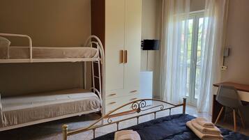 A room with bunk beds, a wardrobe, a desk, a chair, and a television.