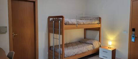 A bunk bed with a ladder, a bedside table with a lamp, and a door with a lock.
