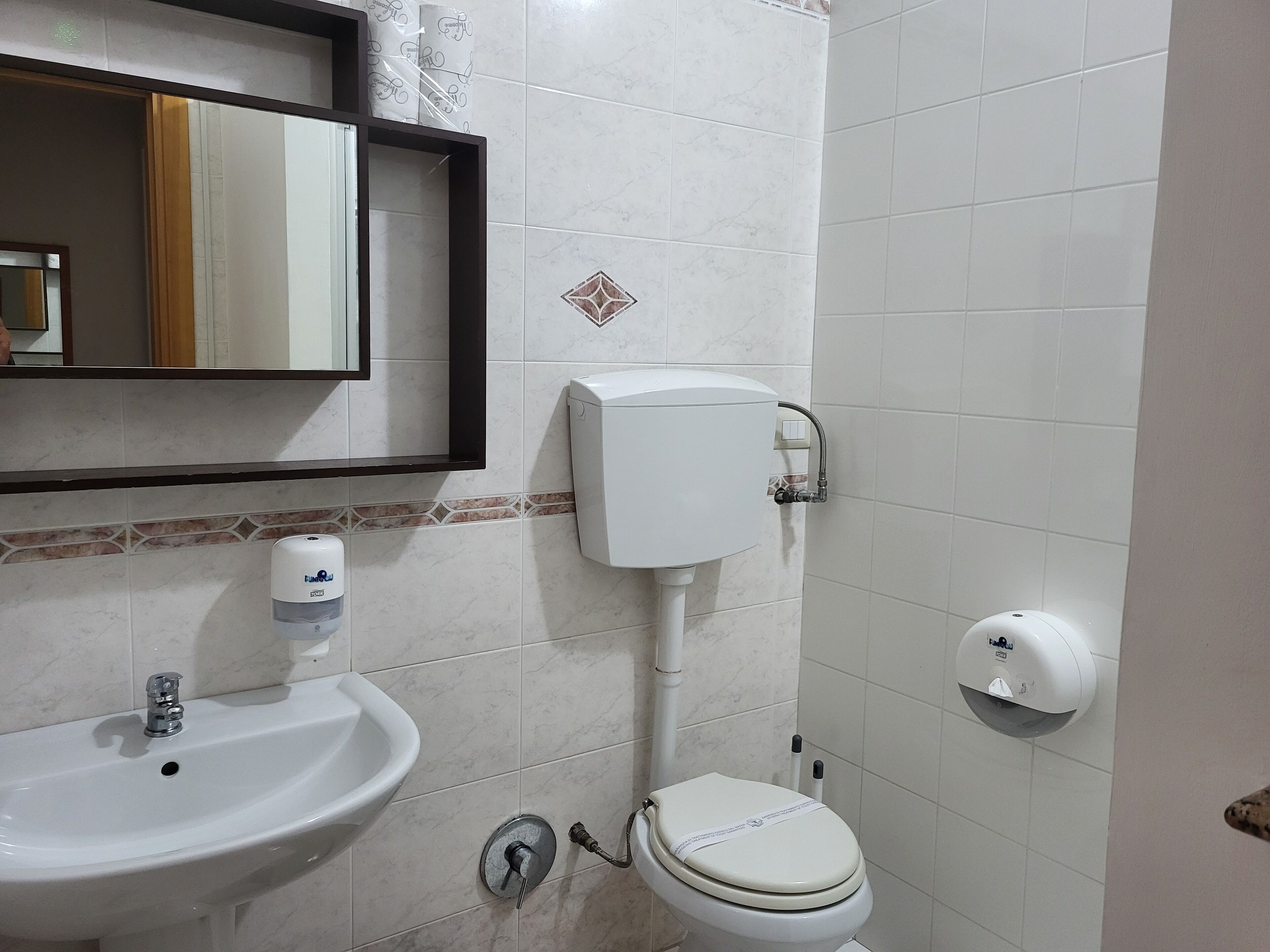 A bathroom with a sink, toilet, and hand dryer.