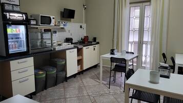 A compact kitchen with a refrigerator, microwave, and coffee maker. There is a small dining area with a table and chairs.