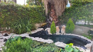 Um jardim com lago, degraus de pedra e estátuas.