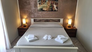 Uma cama bem arrumada com duas almofadas, duas mesas de cabeceira com abajures e um quadro na parede.