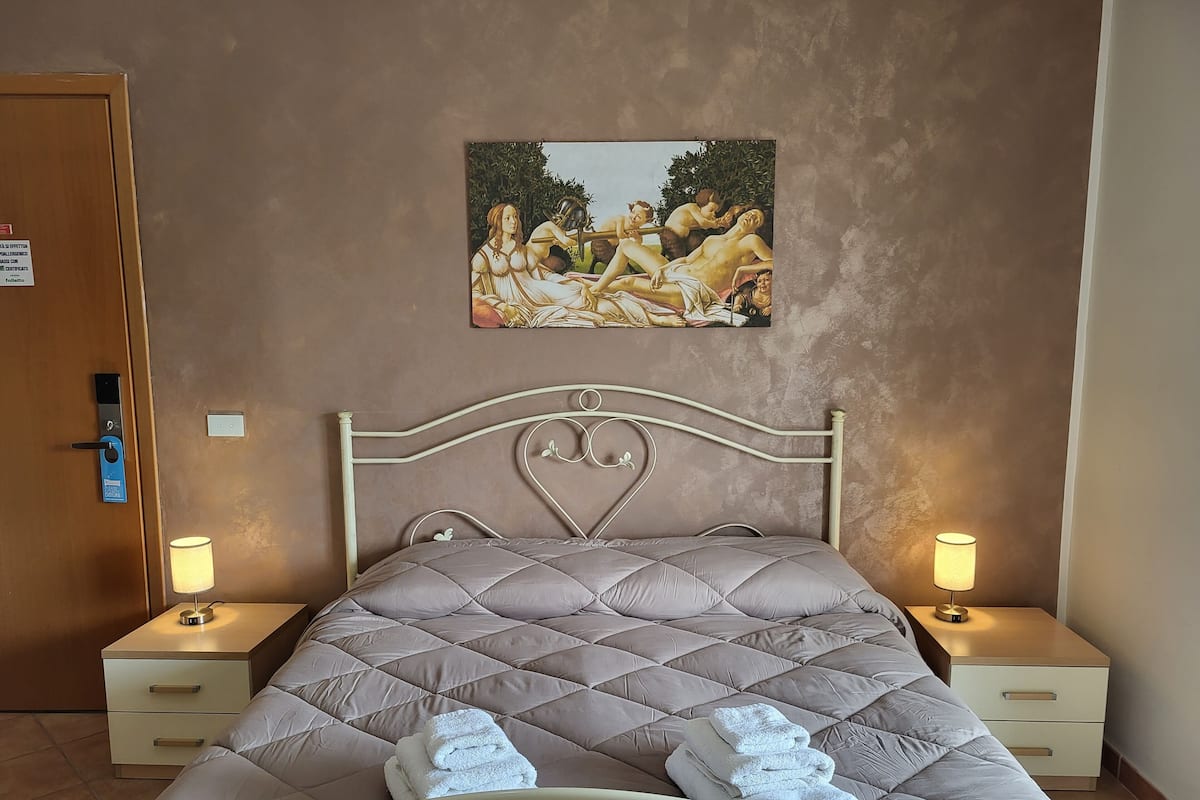Ein Hotelzimmer mit einem Bett, zwei Nachttischen mit Lampen, einem Bild an der Wand und einer Tür mit Schloss.