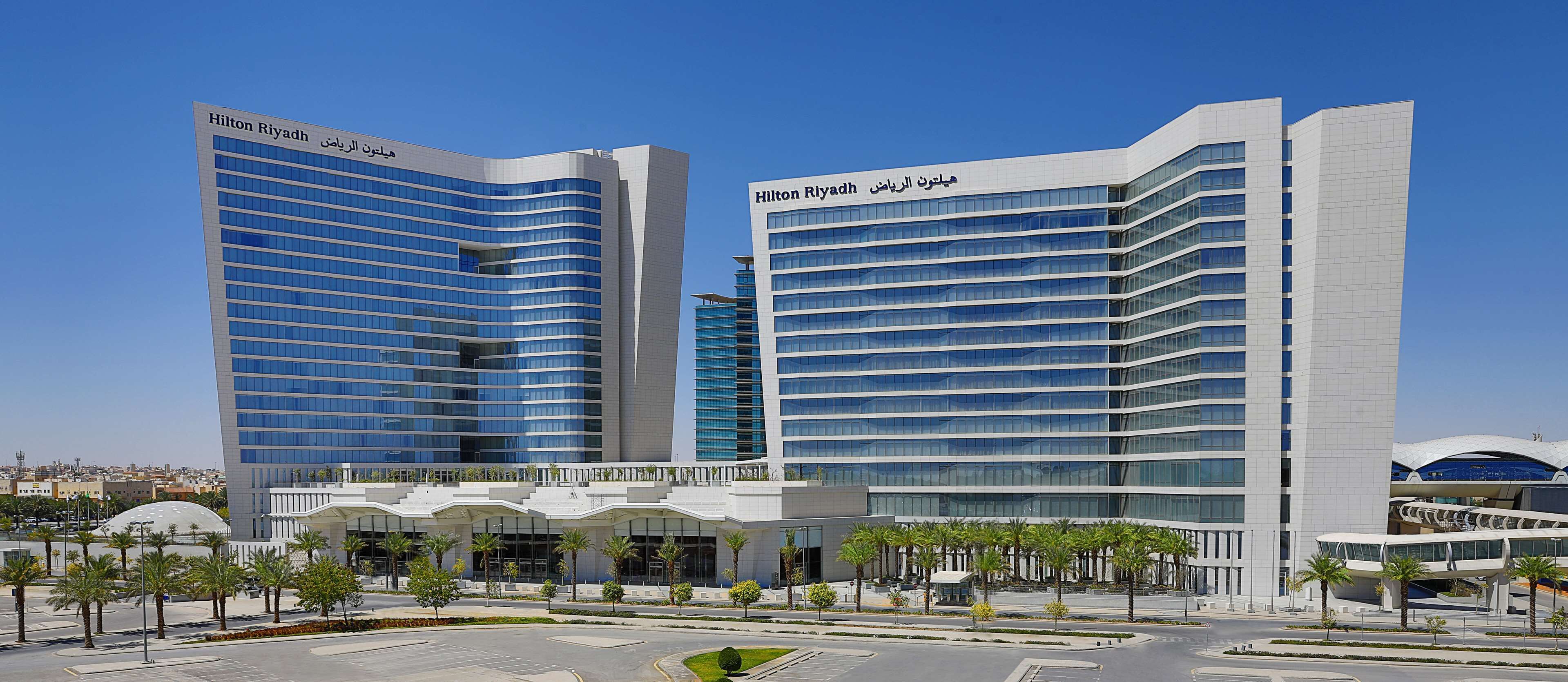 A modern hotel with a curved facade, multiple floors, and a prominent entrance with a covered area.