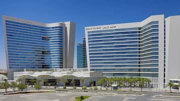 A modern hotel with a curved facade, multiple floors, and a prominent entrance with a covered area.