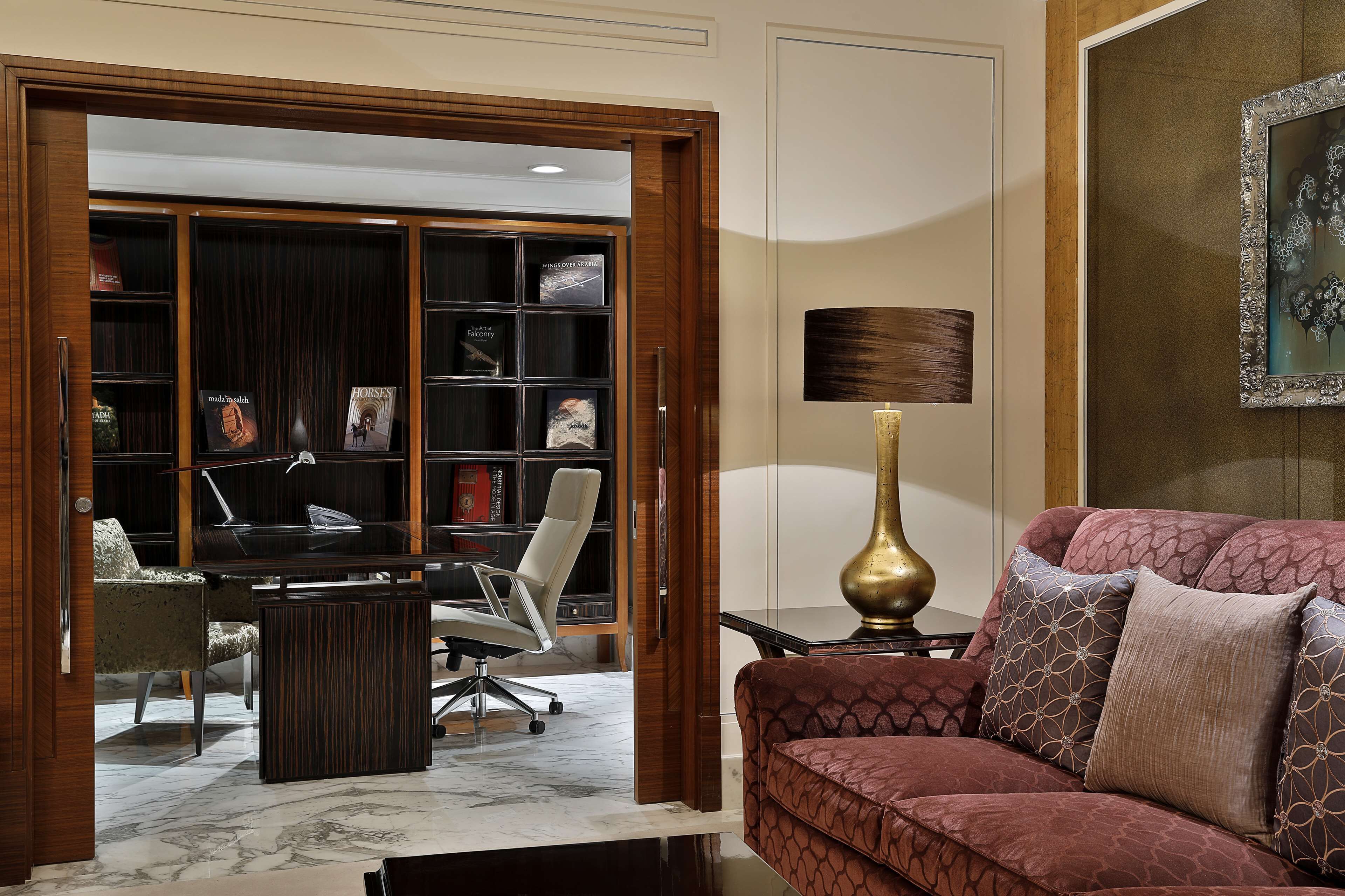 A well-lit office space with a desk, office chair, and a bookshelf filled with books.