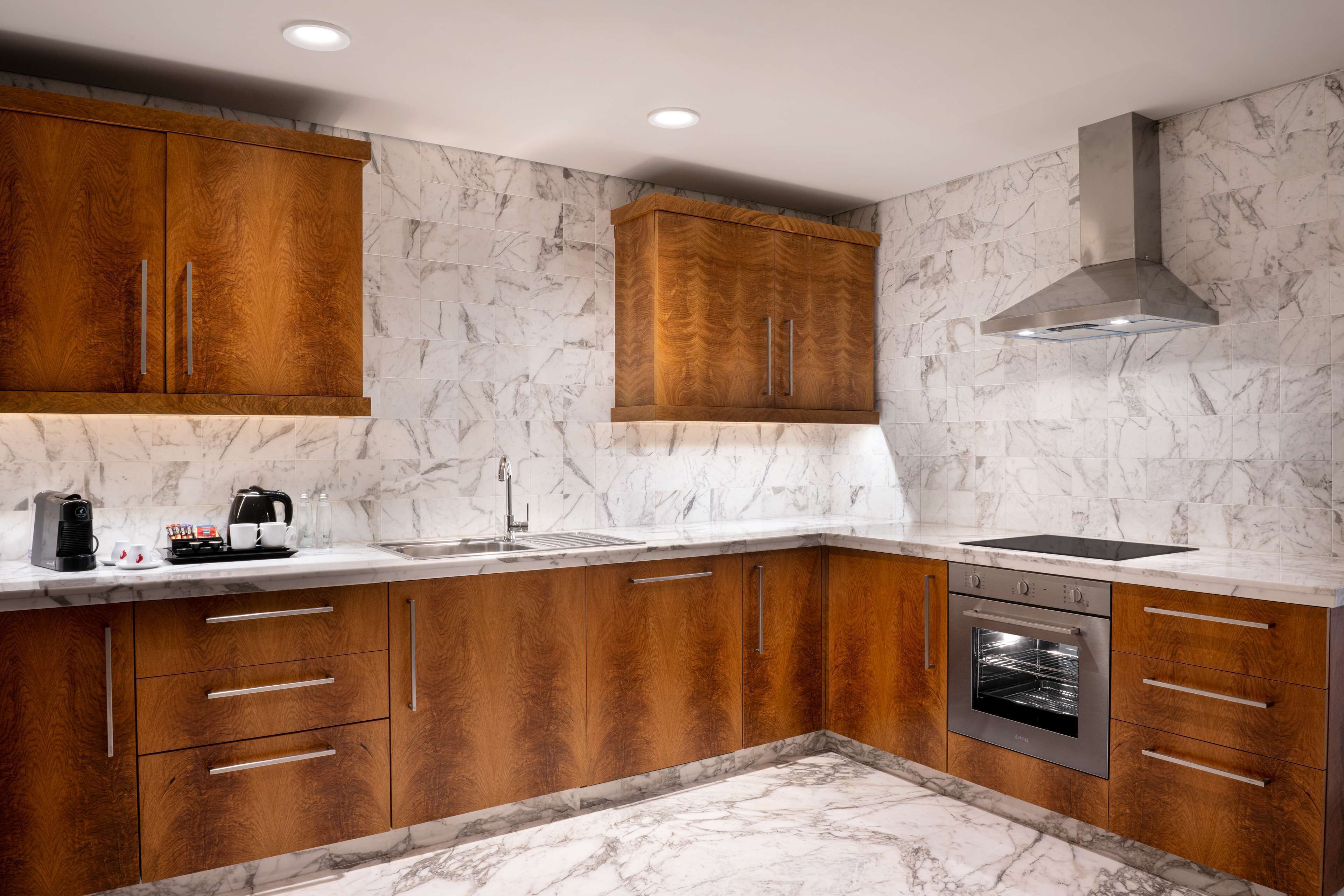 A modern kitchen with wooden cabinets, a built-in oven, and a marble backsplash.