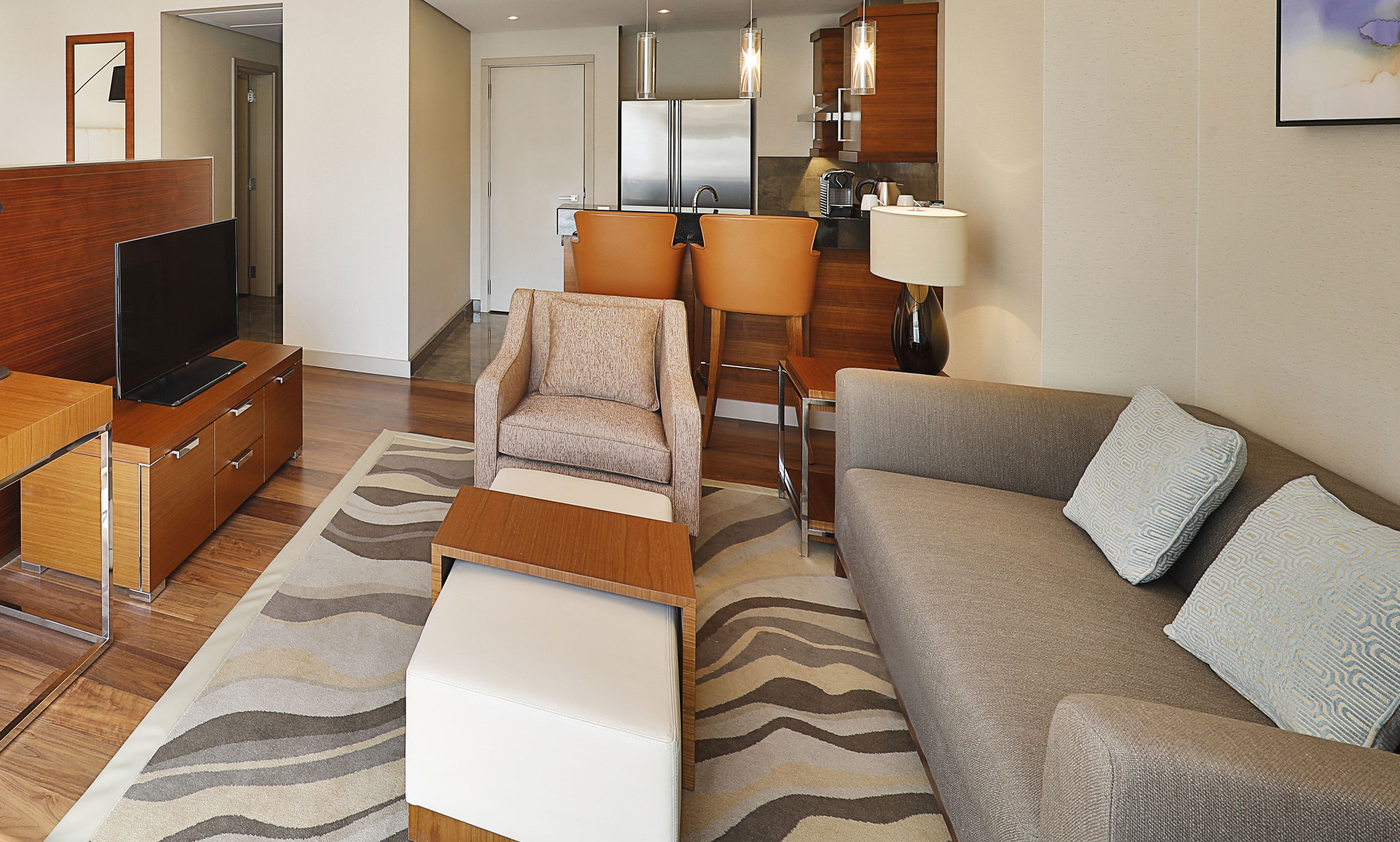 A modern hotel room with a living area, a dining area, and a kitchenette.