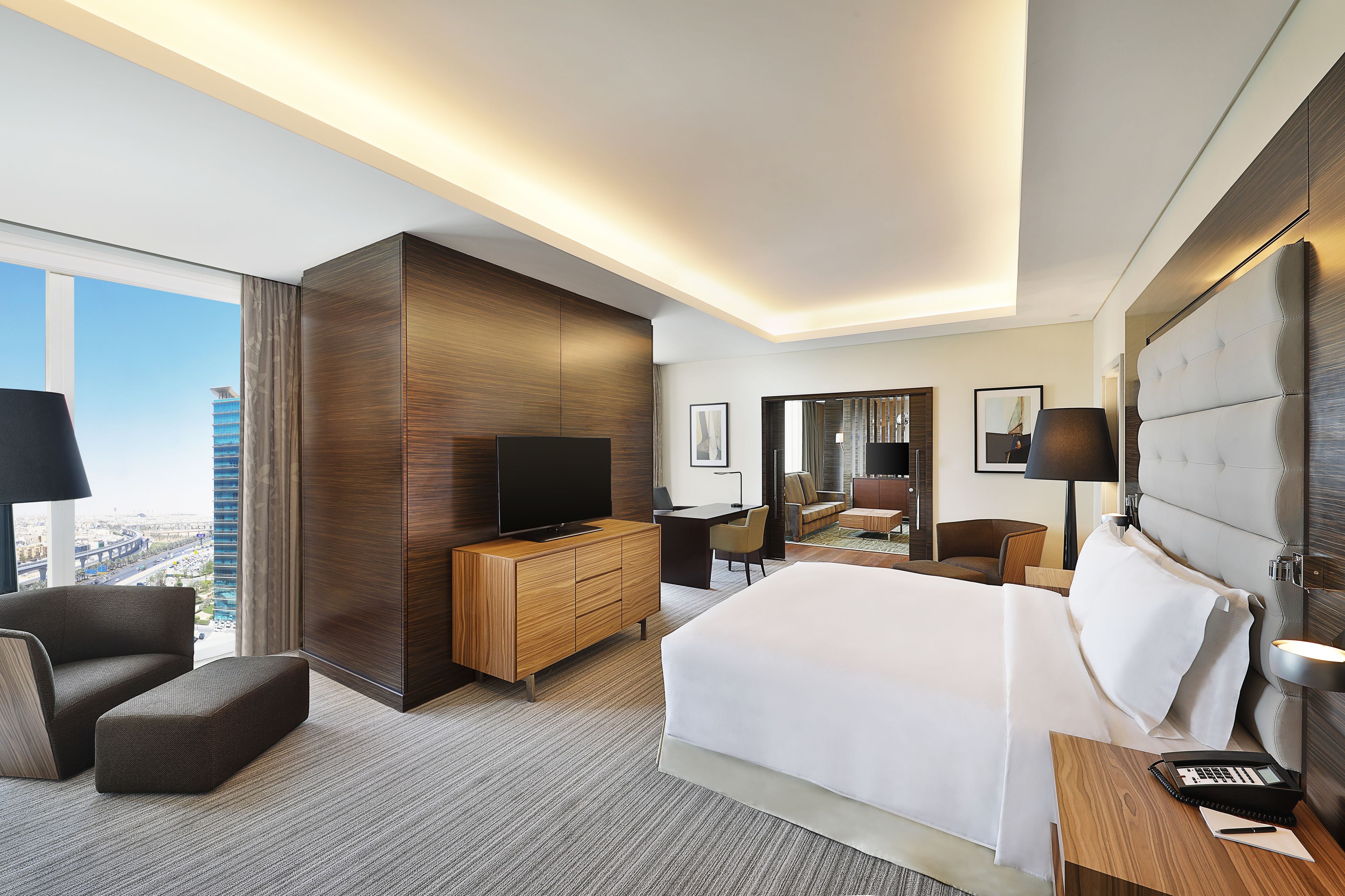 Een moderne hotelkamer met een groot bed, een flatscreen televisie, een bureau en een comfortabele zithoek.
