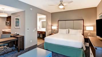 Quarto de hotel com cama, escrivaninha, cadeira e televisão.