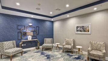 A conference room with a blue accent wall, patterned chairs, a round table, and a small white table.
