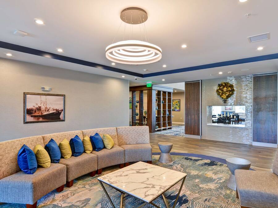 Un lobby moderno con un sofá modular, una mesa de centro de mármol y una alfombra estampada.