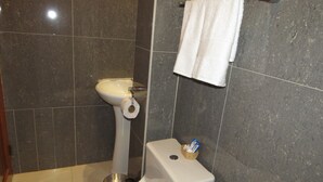 A bathroom with a toilet, sink, and a towel hanging on the wall. - Hatun Pueblo Inn (Machu Picchu)