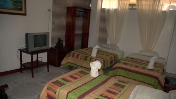 A hotel room with two beds, a television on a small table, and a painting on the wall. - Hotel Salinas (Puerto Ayora)