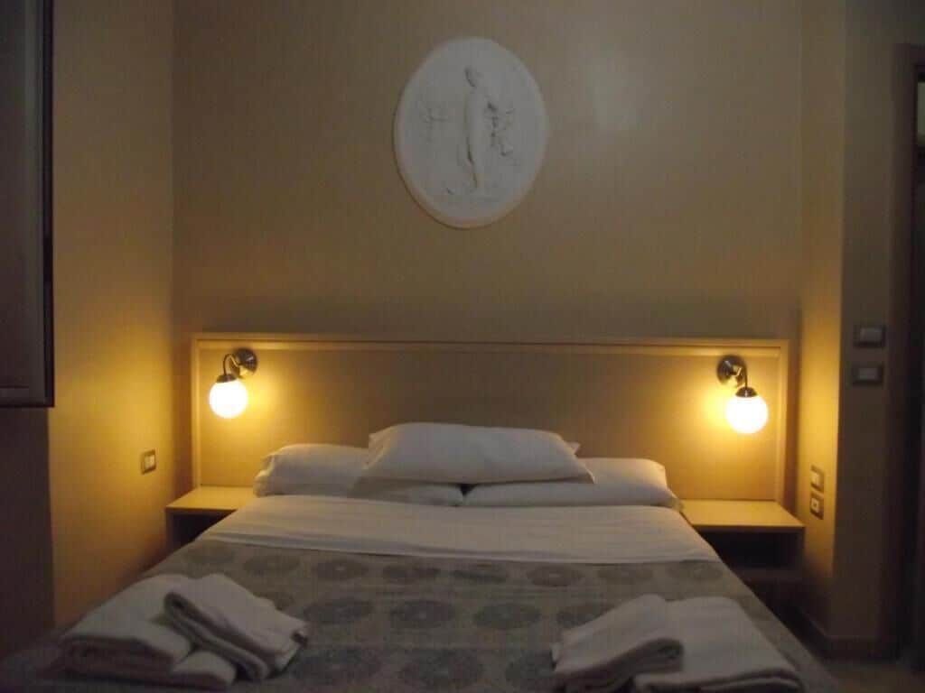 Una habitación de hotel con una cama, dos lámparas de noche y una obra de arte colgada en la pared.