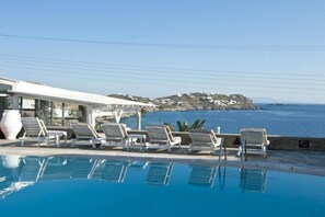 Zona de piscina con sillones de descanso y vista al mar.