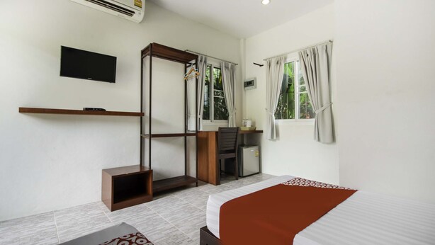 Une chambre d’hôtel comprenant un lit, un bureau, une chaise, une télévision et une armoire.