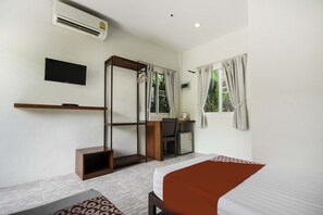 Ein Hotelzimmer mit Bett, Schreibtisch, Stuhl, Fernseher und Kleiderschrank.
