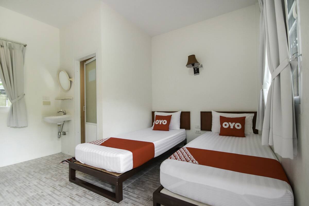 A hotel room with two beds, a bathroom, and a window with curtains.