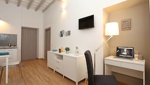 Una habitación moderna y bien iluminada con escritorio, silla y televisor en la pared.