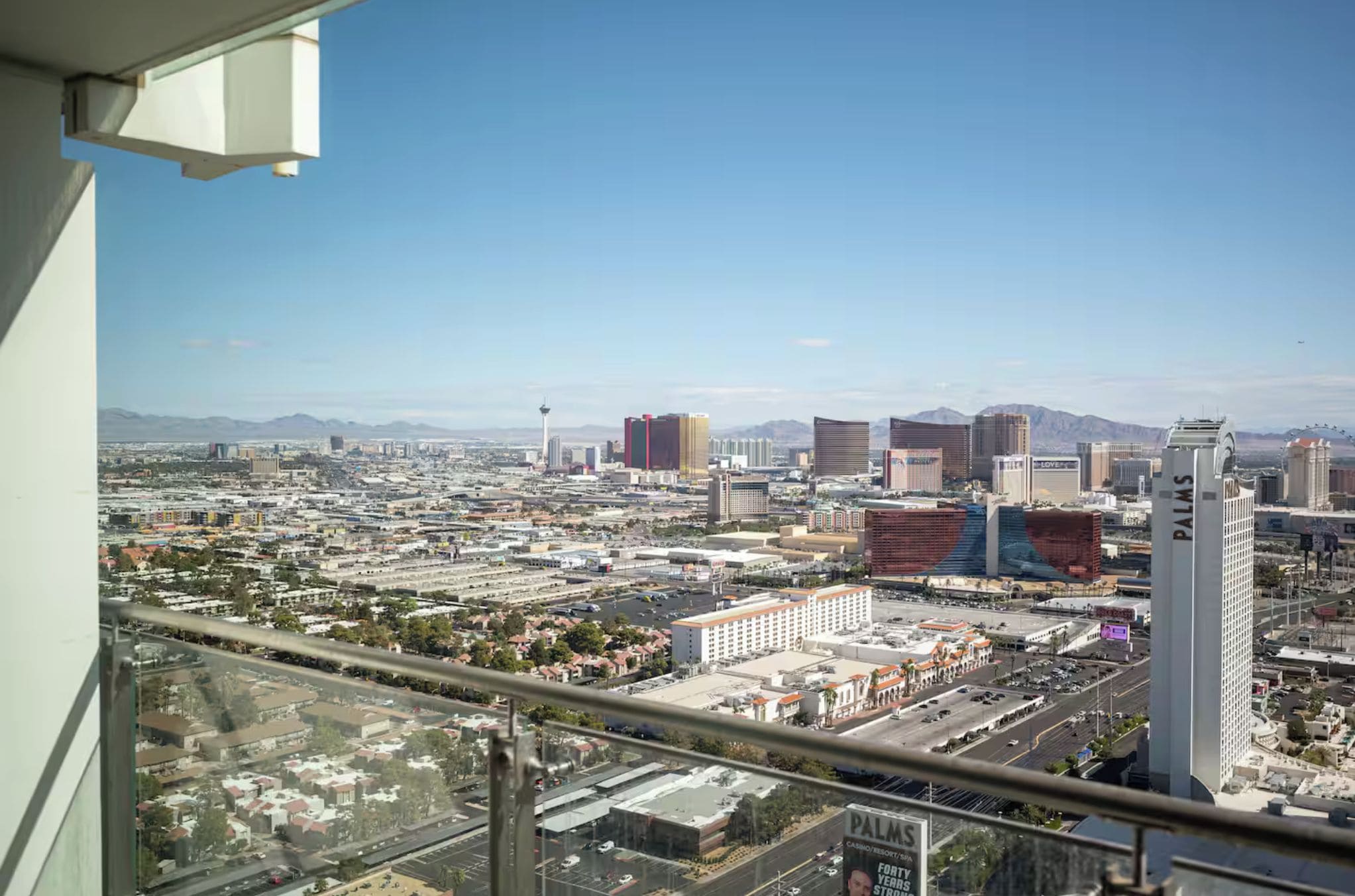 A cityscape with a prominent building labeled "PALMS" in the foreground, a variety of other buildings, and a clear sky.