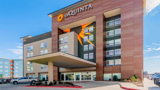 Un hôtel La Quinta au design moderne, avec un logo solaire bien visible et une grande entrée.