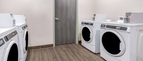A laundry room with two front-loading washing machines and a door.