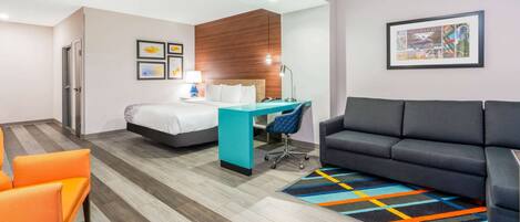Une chambre d’hôtel avec un lit, un bureau, un canapé et un tapis coloré.