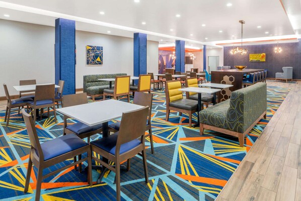 A hotel lobby with multiple seating areas, including tables and booths, and a central counter.