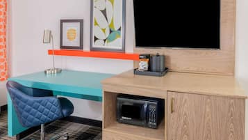 Un espace de bureau moderne avec un bureau de couleur turquoise, une chaise bleue, un téléviseur fixé au mur et un four à micro-ondes dans un meuble en bois.