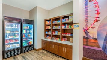 A room with two refrigerated display cases, a wooden cabinet with snacks, and a mural of a Ferris wheel.