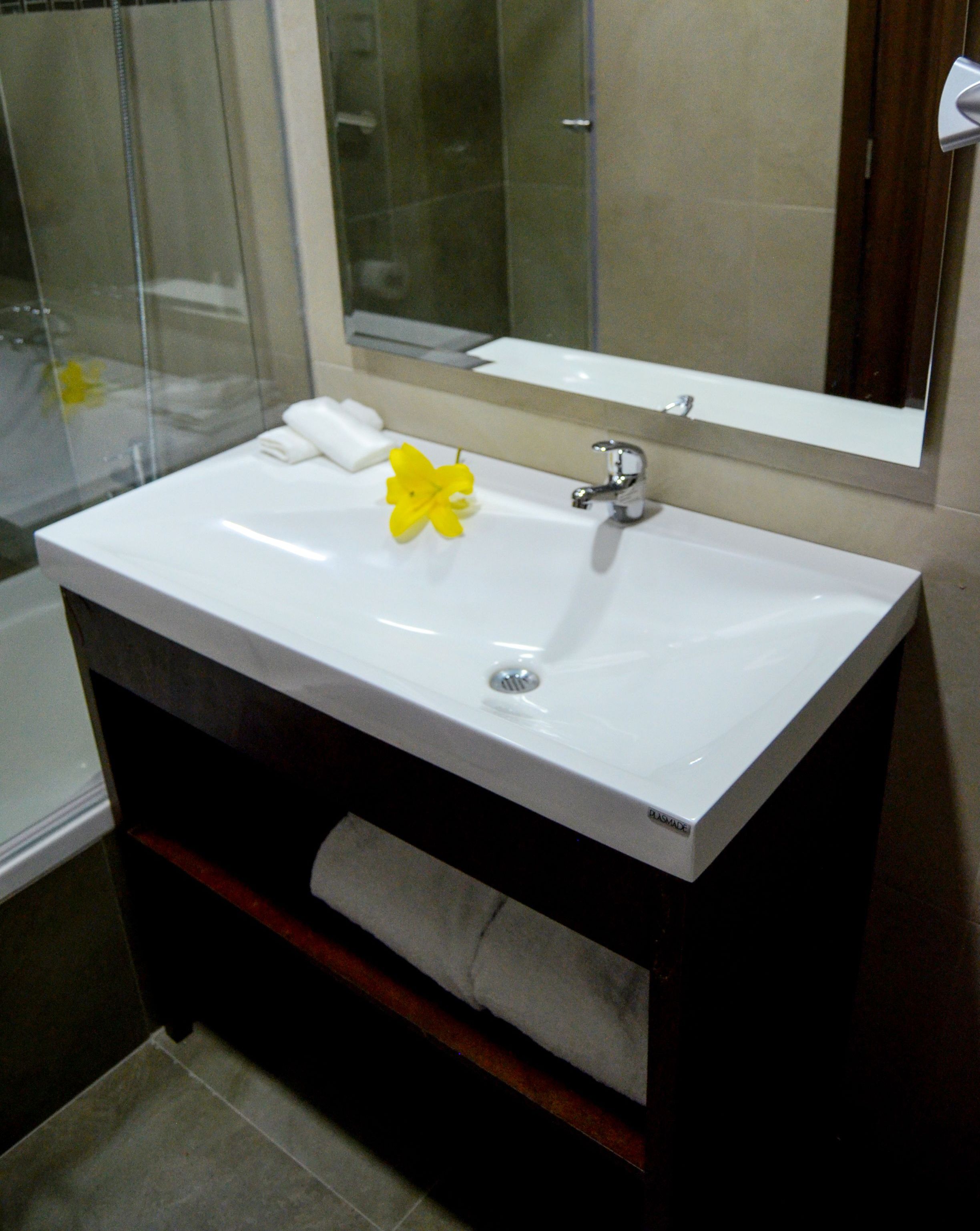 Un baño con lavamanos blanco, un espejo y zona de ducha.