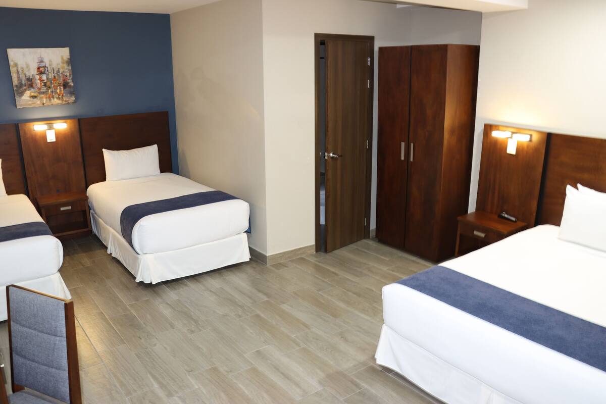 Habitación de hotel con dos camas, un armario de madera y un cuadro en la pared.