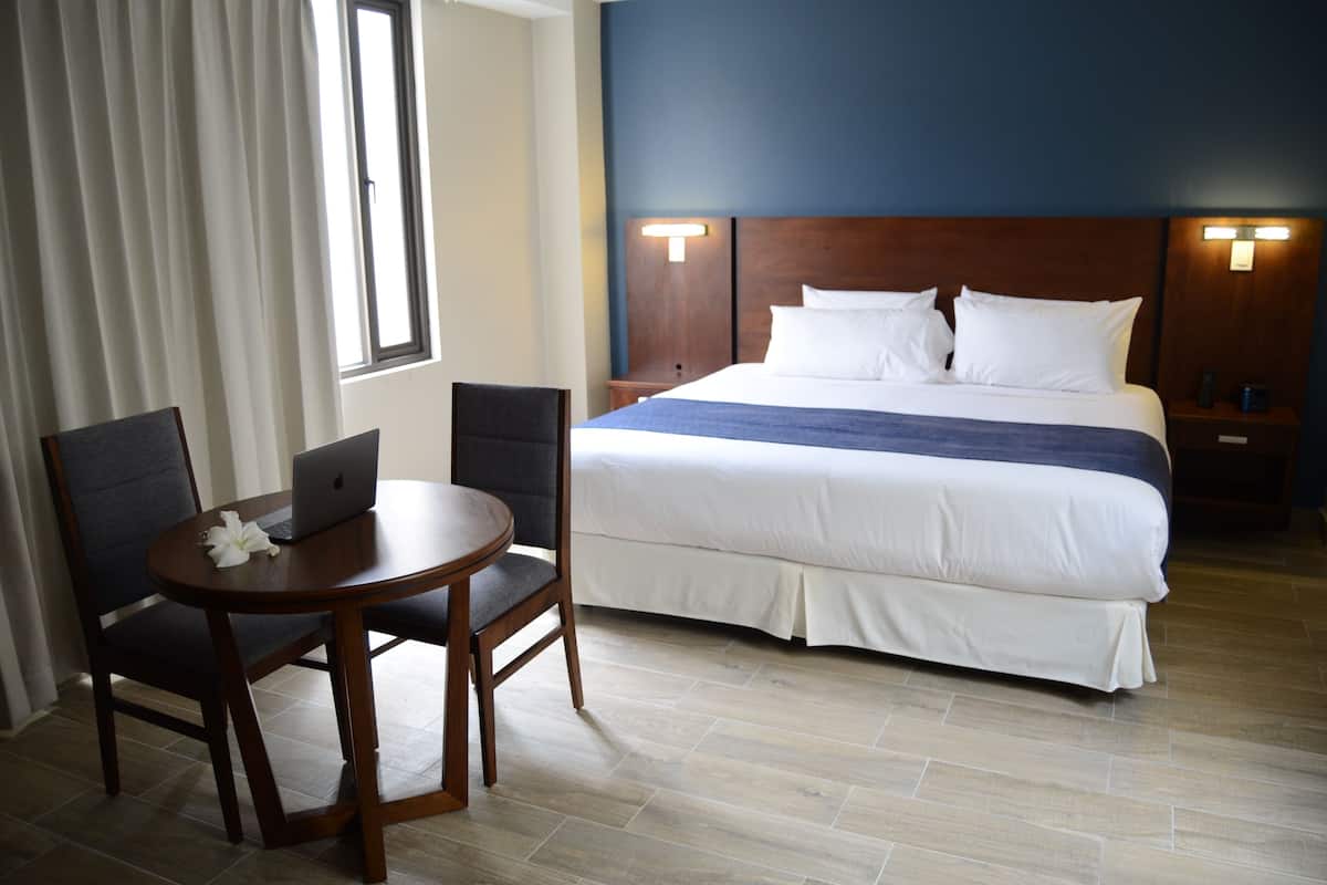 Una habitación de hotel con una cama, un escritorio con una computadora portátil y una silla.